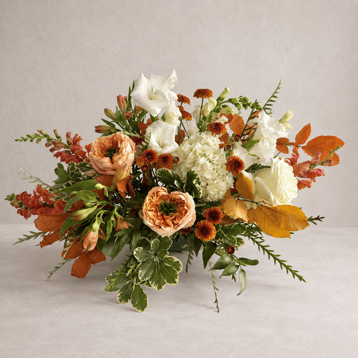 Thanksgiving centerpiece in peach, cream and rust on a neutral grey background